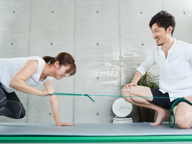 トレーナーに励まされながらパーソナルトレーニングを受ける女性